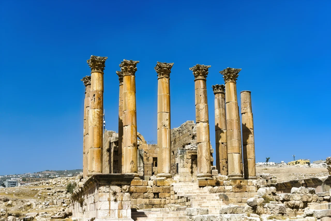 Six colonnes corinthiennes aux chapiteaux dorés se dressent parmi les ruines d'un temple antique