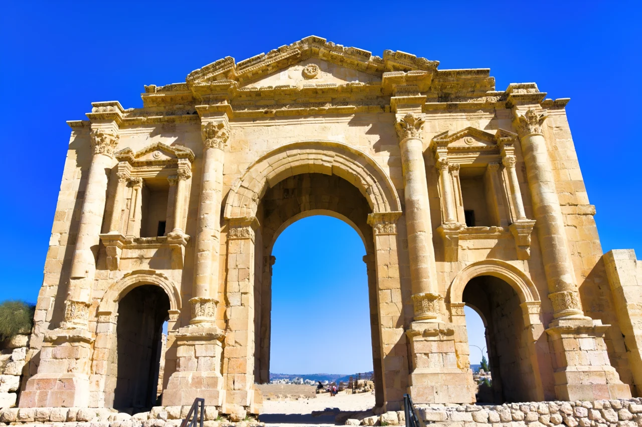 Façade antique romaine à colonnes corinthiennes et trois arcs en plein cintre sur fond de ciel bleu